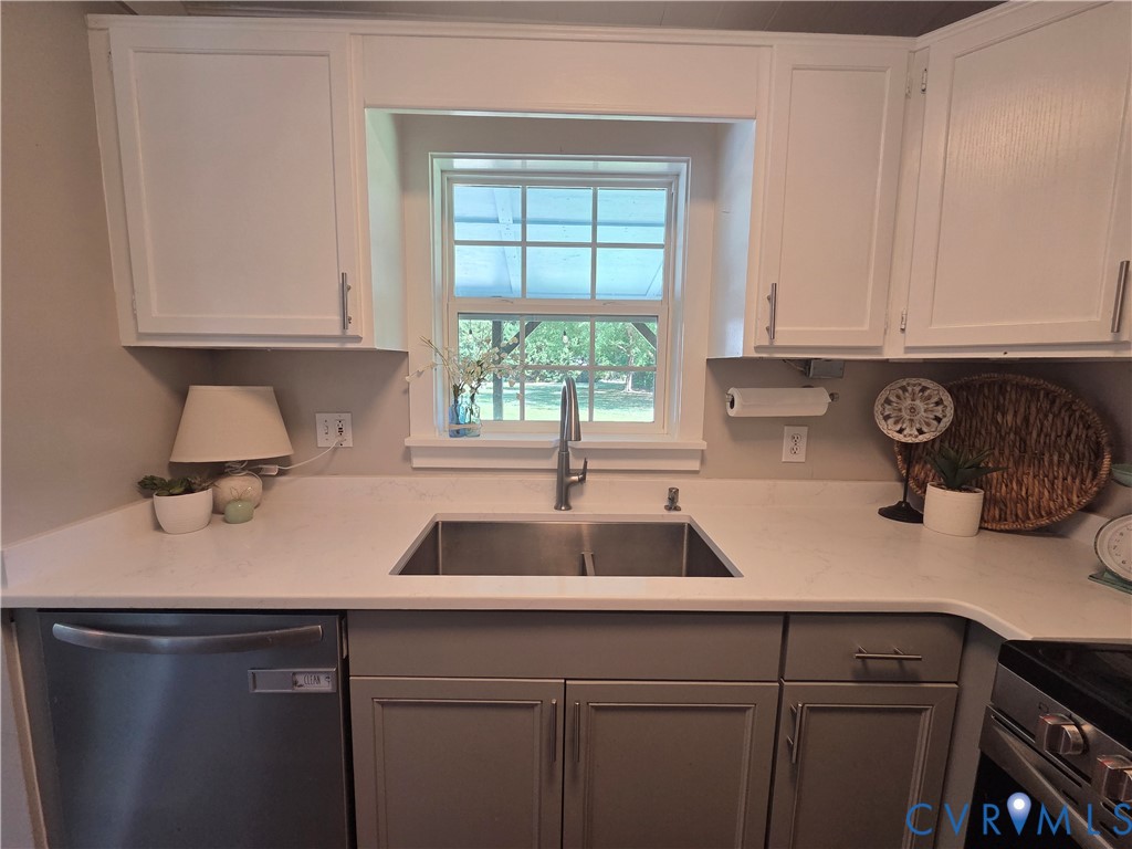 Kitchen featuring shaker-style cabinetry, white solid-surface countertops, dual-basin stainless steel sink, gooseneck faucet, and stainless steel dishwasher