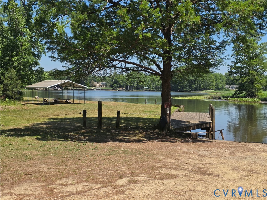 Waterfront grounds featuring a private wood-plank dock, metal-roofed pavilion, mature trees, and direct access to the lake