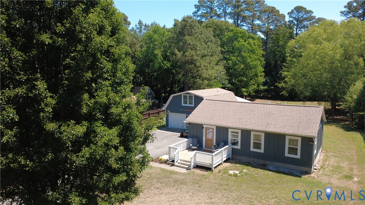 Single-story residence featuring vertical siding, a paved driveway, detached two-story outbuilding, and a raised exterior deck