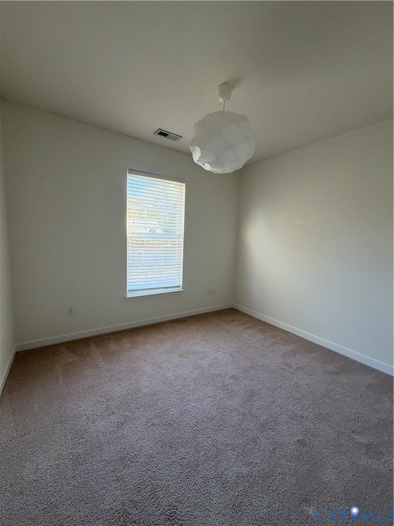 Neutral-toned carpeting, single-pane window with integrated blinds, and spherical geometric pendant lighting