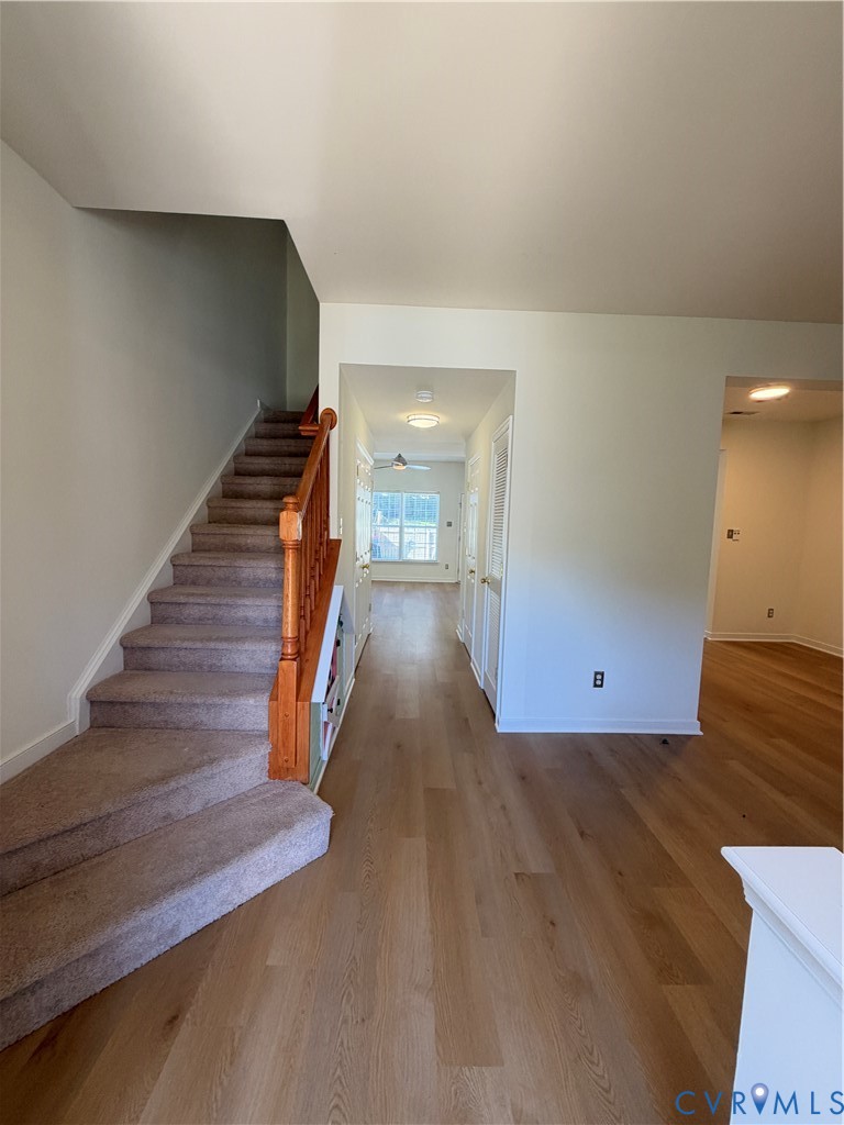 Wood-finish flooring, staircase with a wooden handrail, and flush-mount ceiling light fixtures