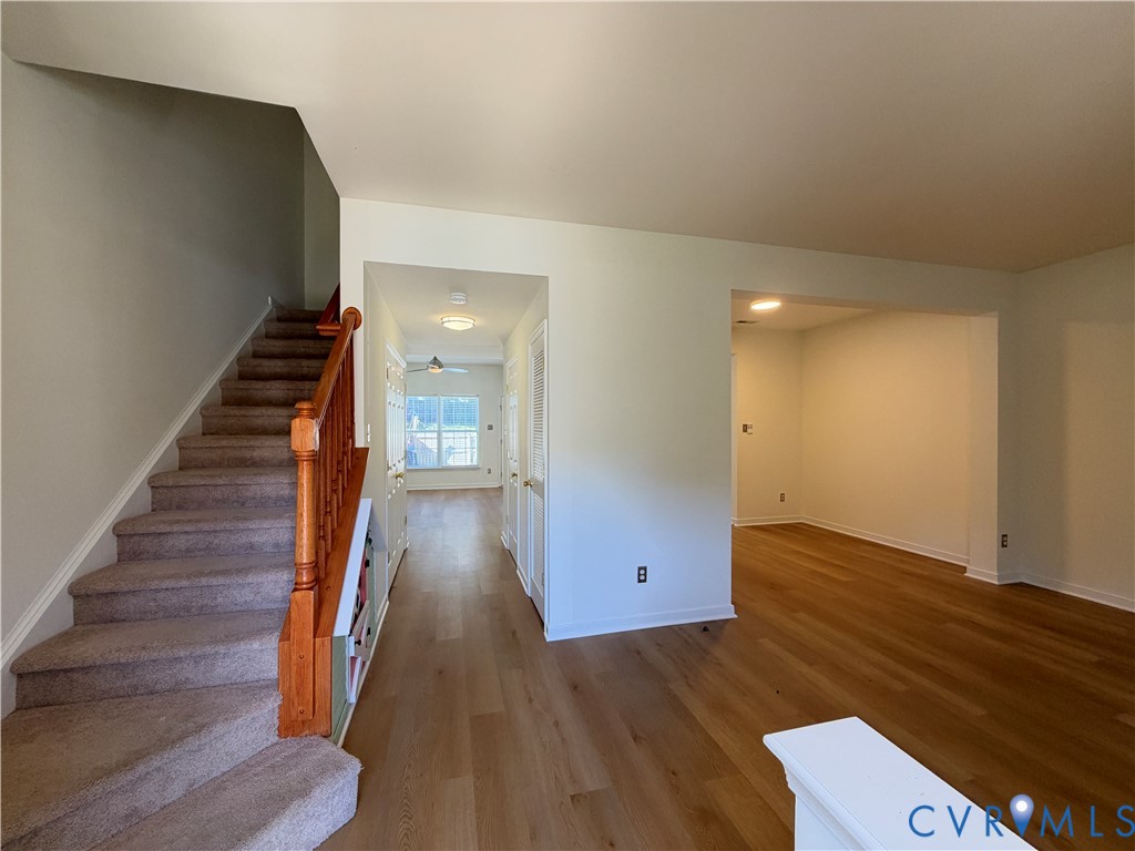 Staircase featuring wood railings and carpeted treads, wood-finish flooring, and recessed ceiling lighting