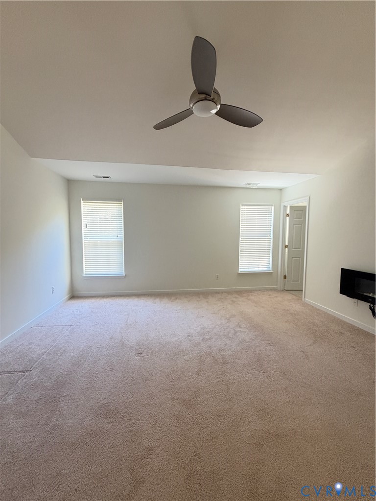Vaulted ceiling featuring a three-blade modern ceiling fan, wall-mounted electric fireplace, and dual windows with integrated blinds