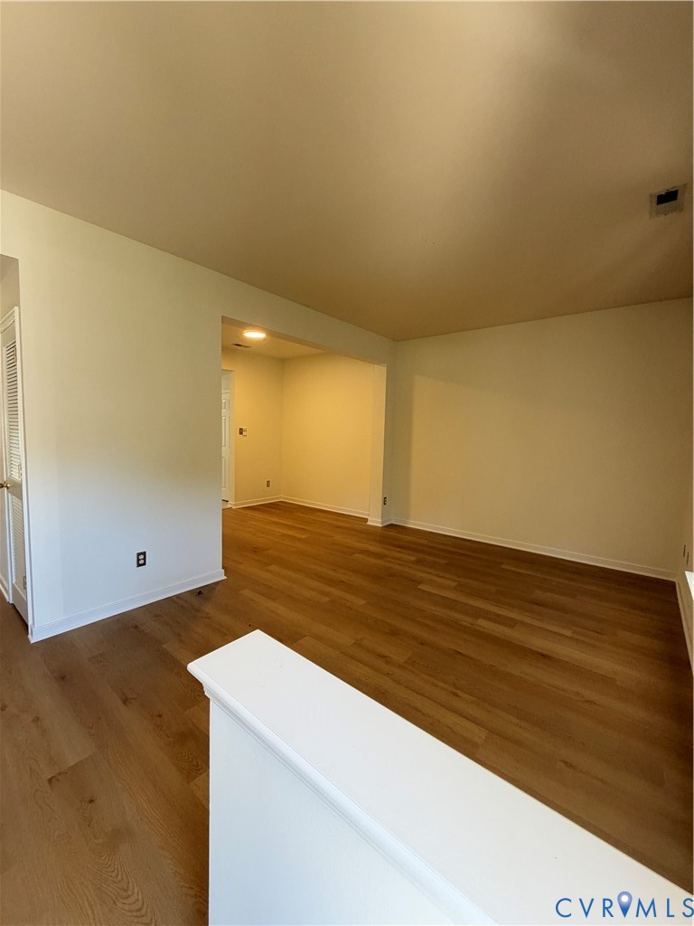 Interior area featuring wood-finish flooring, white walls, and a partial wall divider