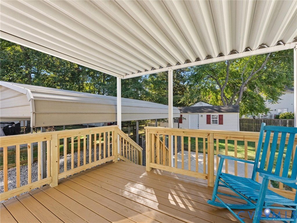 Covered deck featuring wood-finish decking, natural wood railings, and a corrugated metal overhead structure