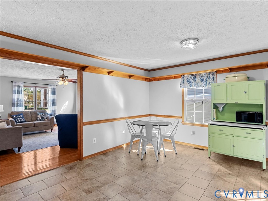 Neutral-toned tile flooring, natural wood-finish crown molding, chair rail detailing, and grid-style windows