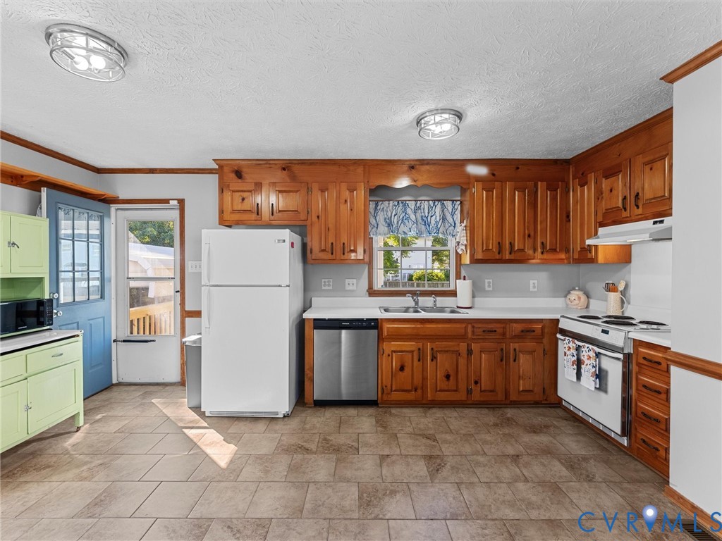 Kitchen featuring natural wood cabinetry, tile flooring, stainless steel dishwasher, and white appliances