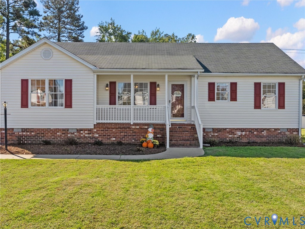 Single-story exterior featuring light-toned vinyl siding, brick foundation, a covered front porch with white railing, and dark red window shutters Single-story exterior featuring light-toned vinyl siding, brick foundation, a covered front porch with white railing, and dark red window shutters