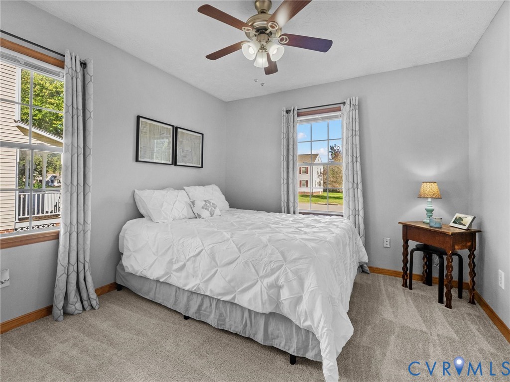 Neutral-toned interior featuring wall-to-wall carpeting, multiple double-hung windows with exterior muntins, and a ceiling-mounted light fixture with a fan