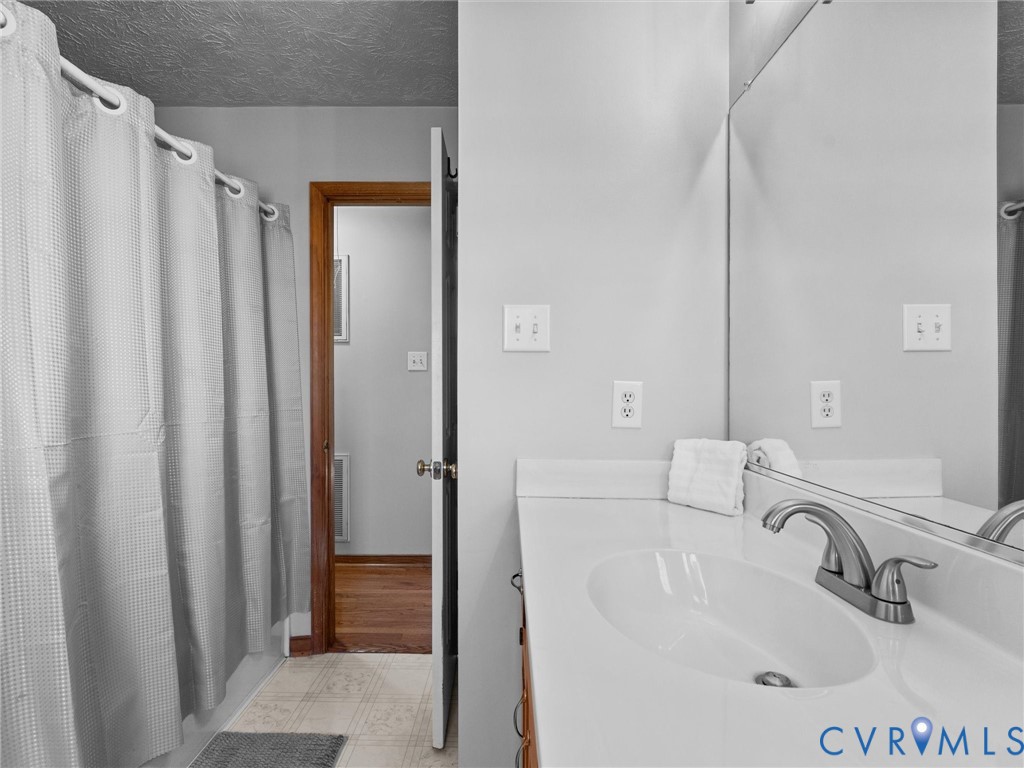 Bathroom featuring a white vanity with a molded basin, brushed nickel faucet, large wall-mounted mirror, and a tub-shower combination