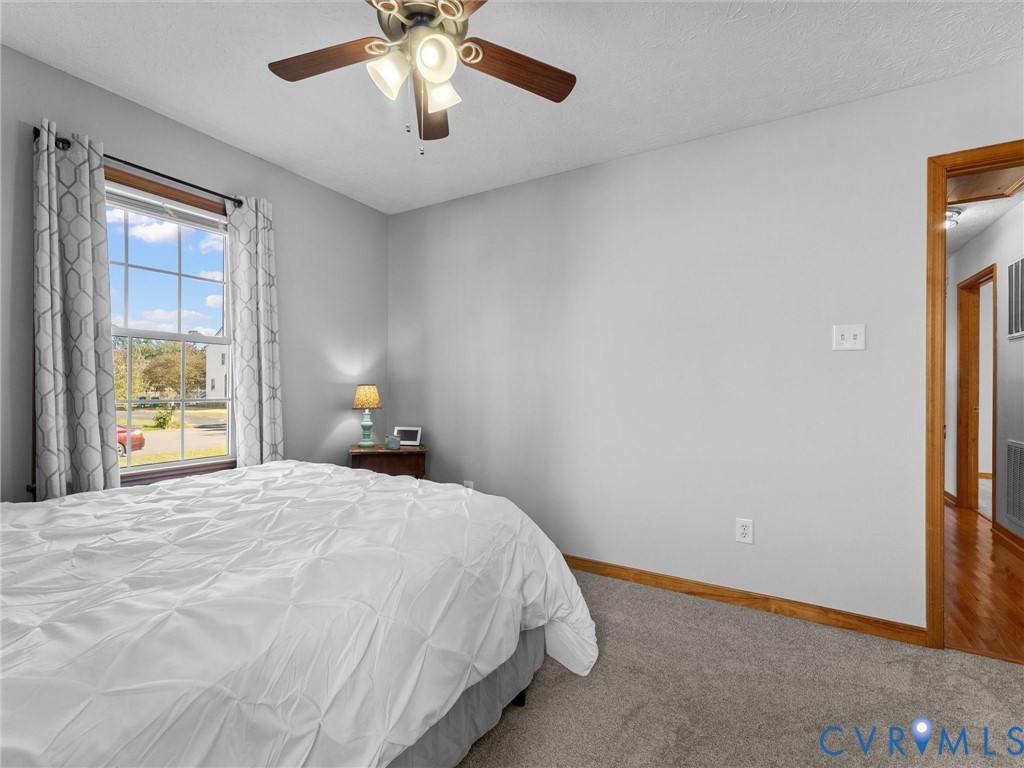 Neutral wall tones, ceiling fan with integrated lighting, window with wooden casing, and wall-to-wall carpeting