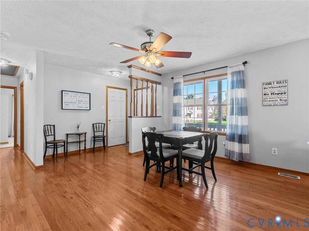 Wood-finish flooring, half-wall with wooden baluster detail, and a multi-light ceiling fan