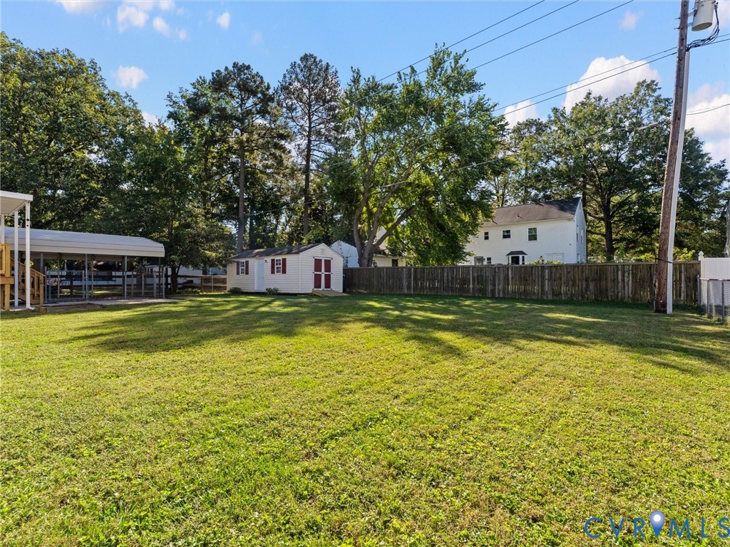 Expansive backyard featuring a level lawn, mature trees, a detached storage shed, and perimeter wood fencing