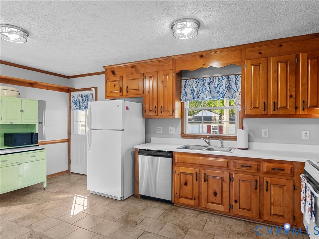 Kitchen featuring wood cabinetry, stainless steel dishwasher, tile flooring, dual-basin sink, and contrasting pastel green built-in hutch
