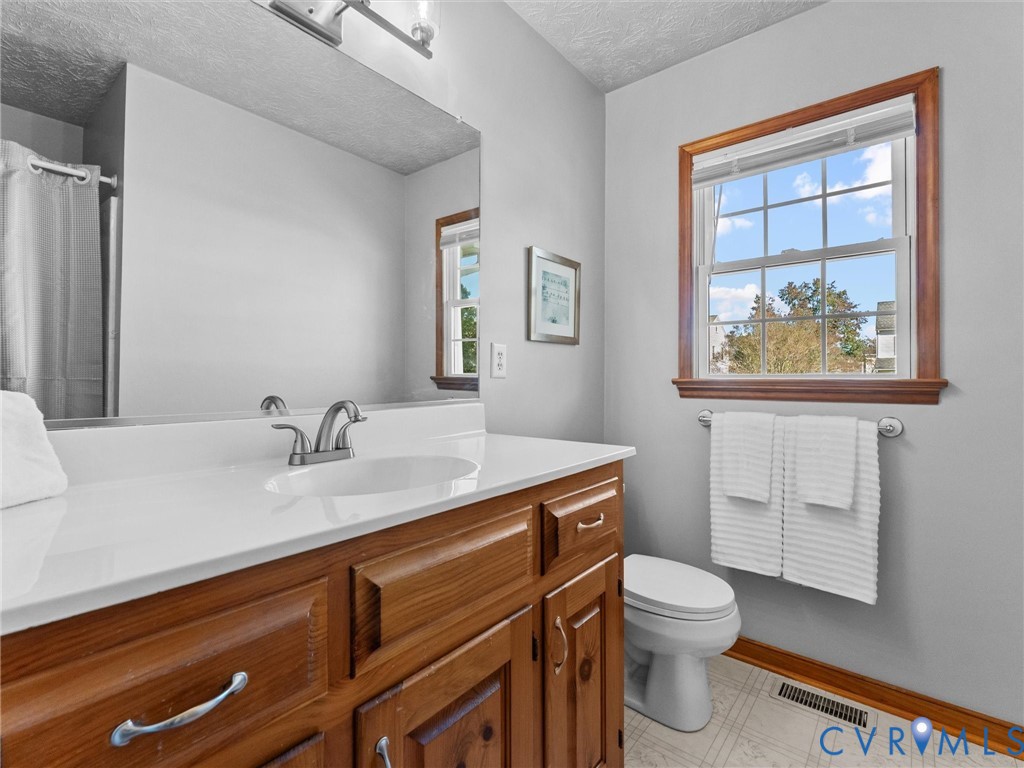 Bathroom featuring a wood vanity with a white countertop, an integrated sink with a brushed-nickel faucet, a large wall-mounted mirror, and a single-hung window with wood trim