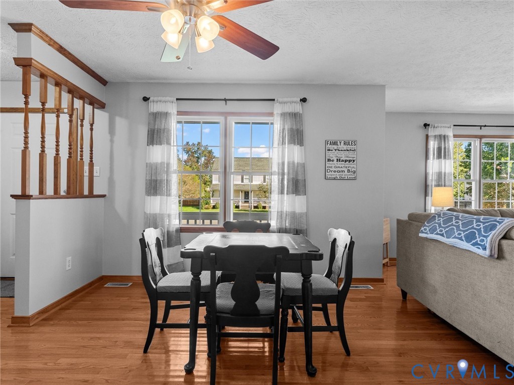 Wood-finish flooring, natural light through multi-pane windows, and wood-railing staircase accent