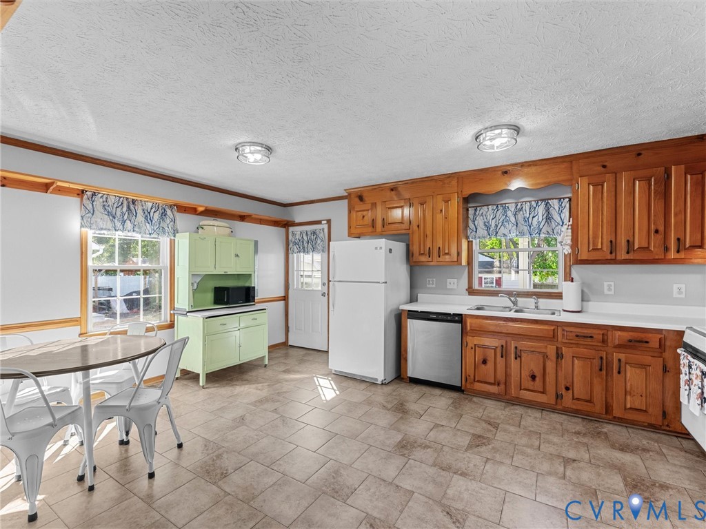 Kitchen featuring natural wood cabinetry, tile flooring, stainless steel dishwasher, white refrigerator, and a built-in hutch