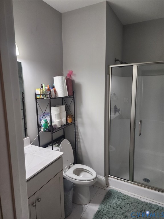 Bathroom featuring a single-sink vanity with a solid-surface countertop, a glass-enclosed shower, and tile flooring