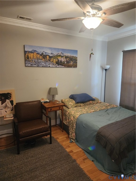 Wood-finish flooring, crown molding, and ceiling-mounted light fixture with a fan