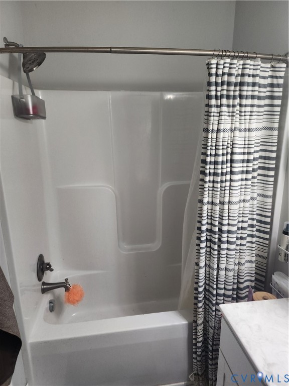 Acrylic tub-and-shower surround with a brushed metal showerhead, matching faucet hardware, and a curved adjustable shower rod