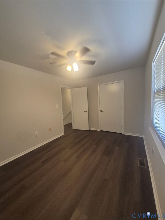 Neutral interior featuring wood-finish flooring, white panel doors, and a ceiling-mounted light fixture with integrated fan