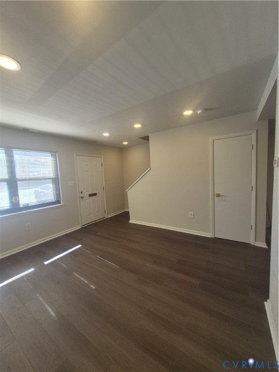 Interior space featuring wood-finish flooring, recessed ceiling lighting, a solid-panel entry door, and painted wall finishes