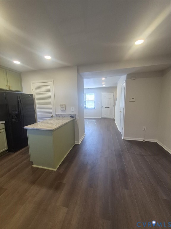 Kitchen area featuring wood-finish flooring, a stone-surface peninsula, recessed lighting, and a louvered pantry door
