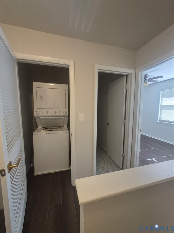 Dedicated laundry closet featuring a stackable washer and dryer, wood-finish flooring, and louvered door