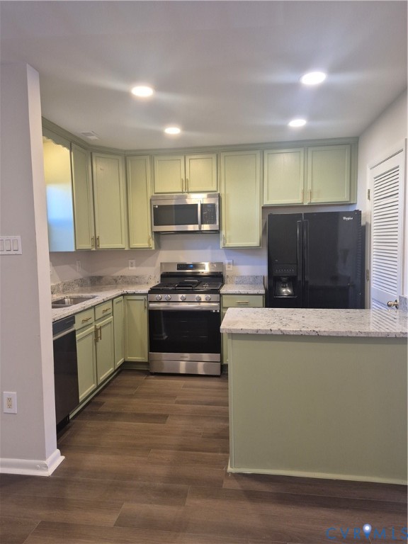 Kitchen featuring light green cabinetry, speckled stone-finish countertops, stainless steel gas range, built-in microwave, and wood-finish flooring