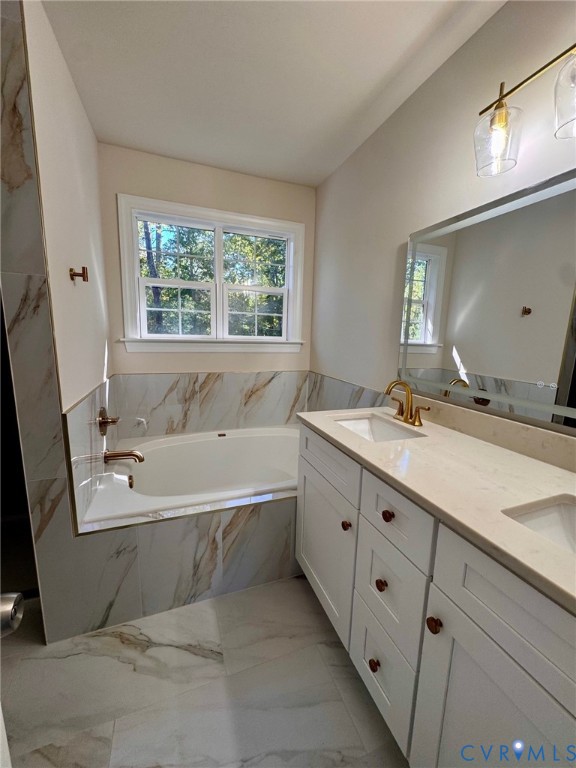 Double vanity with white cabinetry, quartz countertop, dual integrated sinks, and brass-tone hardware