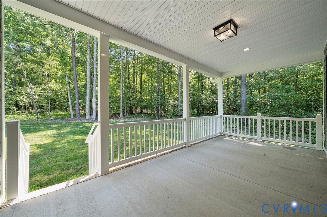 Covered porch featuring concrete flooring, white beadboard ceiling, flush-mount lighting, and white railings