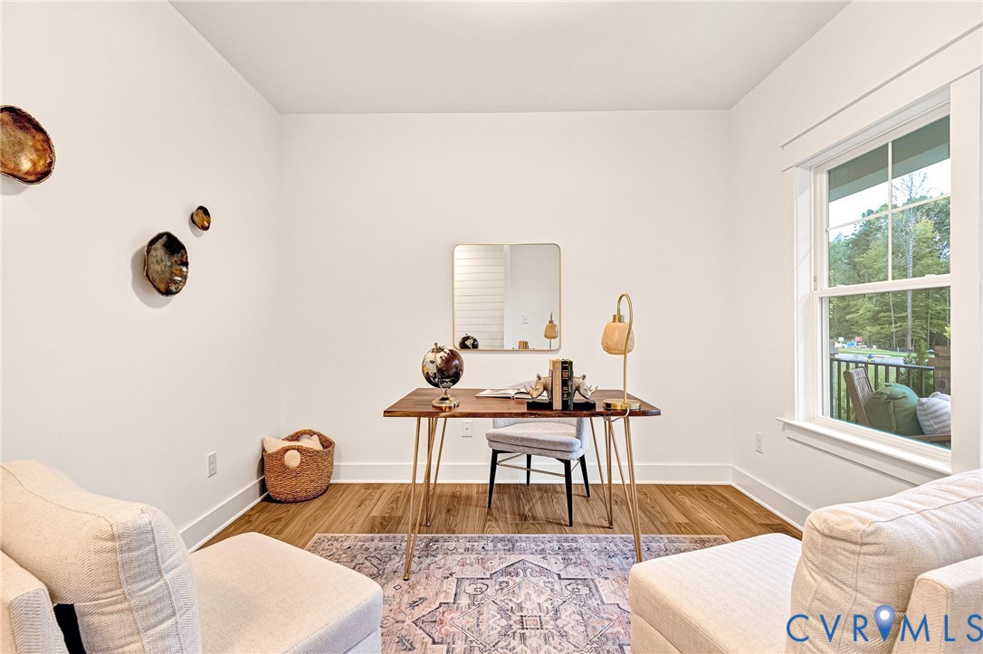 Bright room featuring crisp white walls, wood-finish flooring, and a window with trim detail