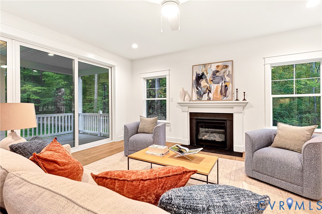 Living area featuring wood-finish flooring, a fireplace with an ornate mantel, sliding glass doors, and large windows with grid muntins
