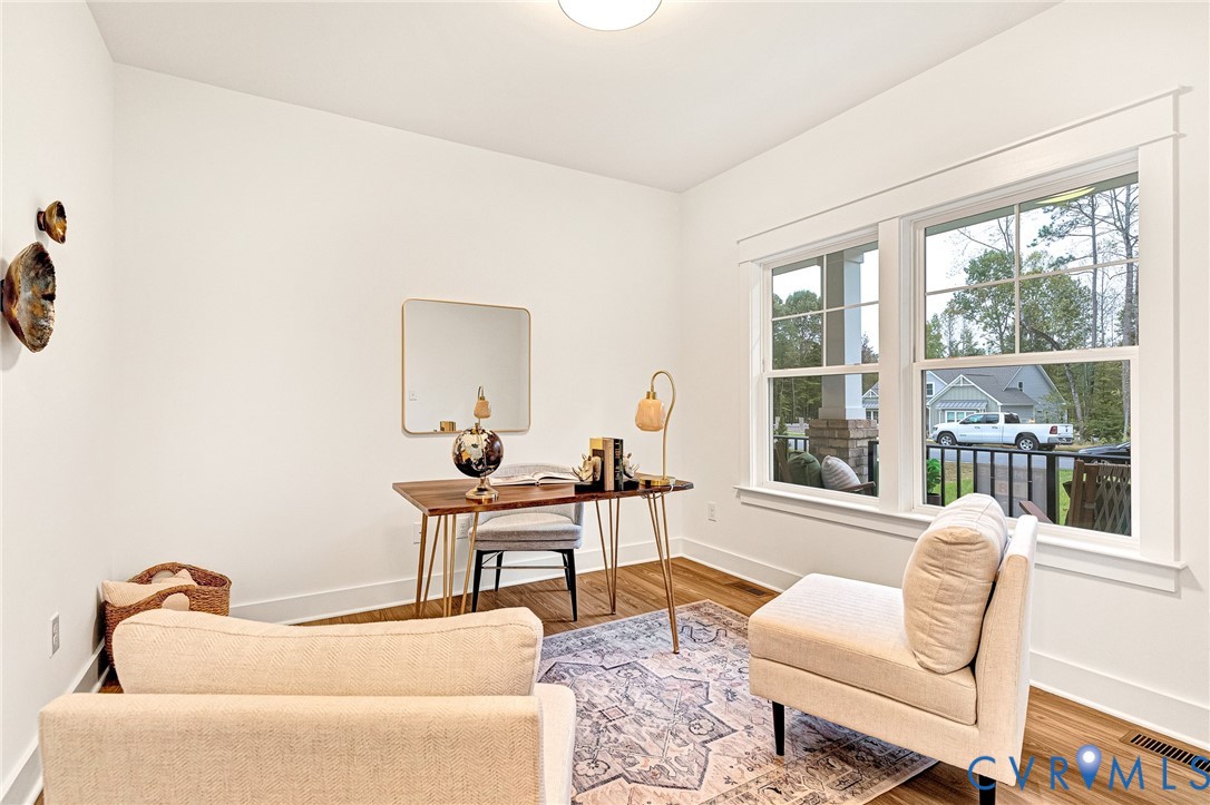 Room featuring wood-finish flooring, white walls, and large windows with grid muntins