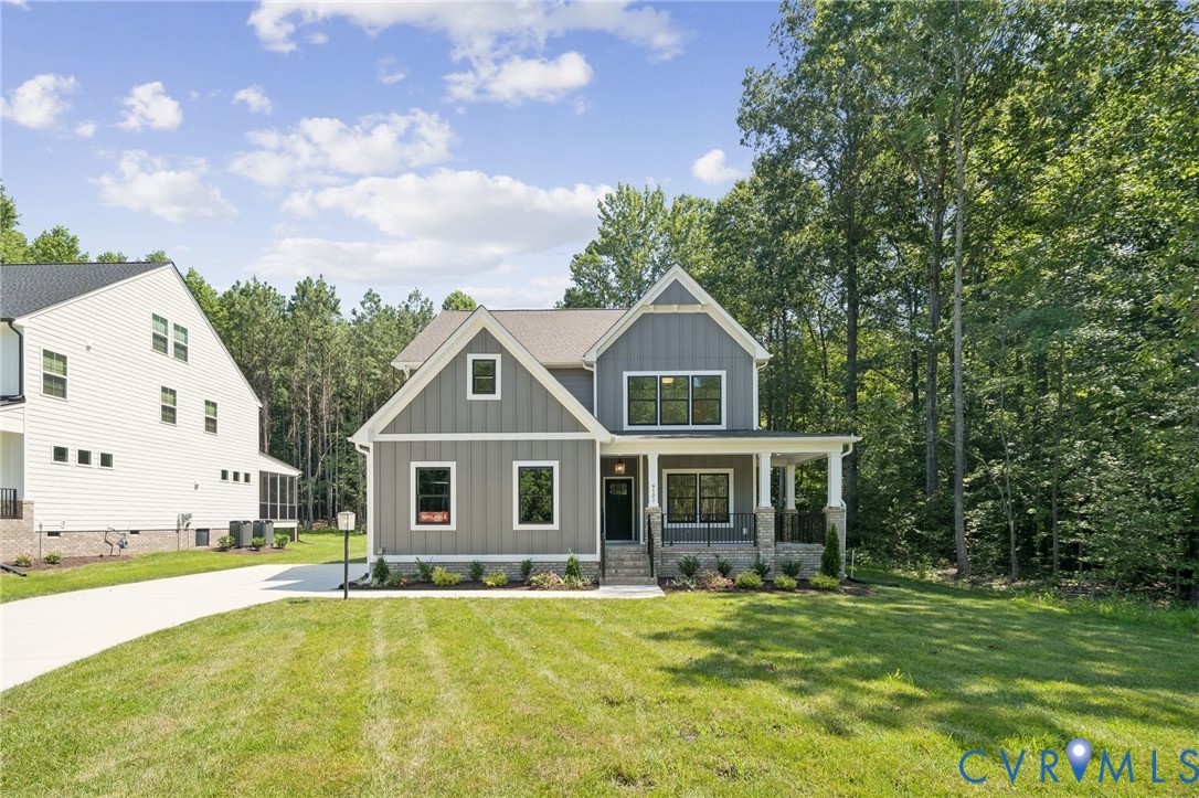 Two-story exterior featuring vertical board-and-batten siding, a stone foundation, a covered front porch with stone columns, and dark-framed windows