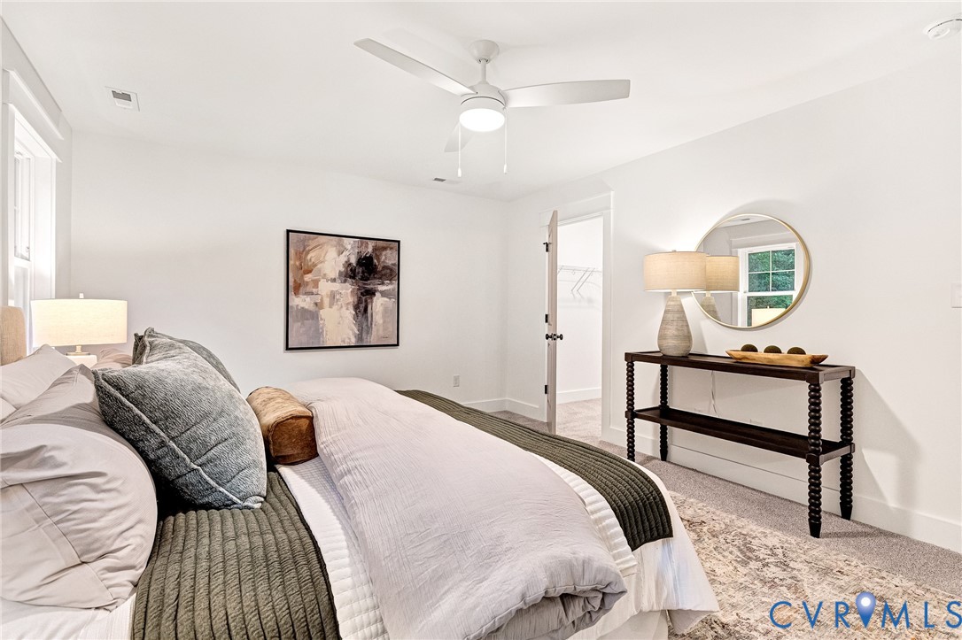 Neutral interior space featuring white walls, wall-to-wall carpeting, and a modern three-blade ceiling fan with integrated lighting