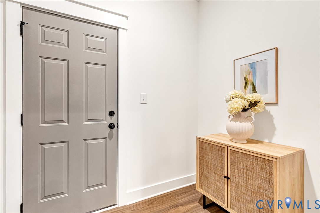 Six-panel door with matte black hardware, crisp white door casing, and wood-finish flooring