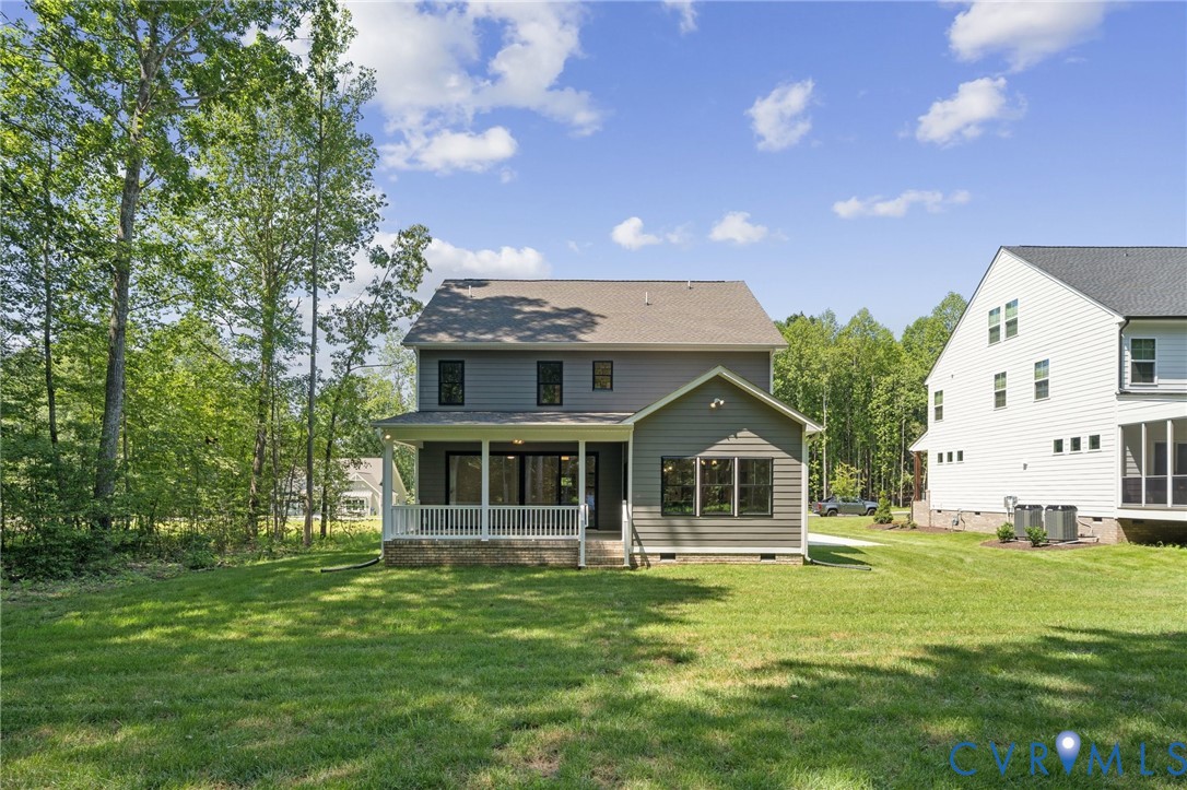 Two-story residence featuring horizontal lap siding, a rear covered porch with white railing, and an expansive lawn