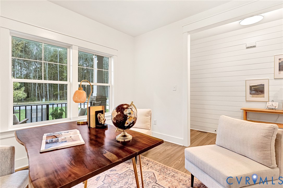 Bright room featuring large multi-pane windows, plank-style wall paneling, and wood-finish flooring