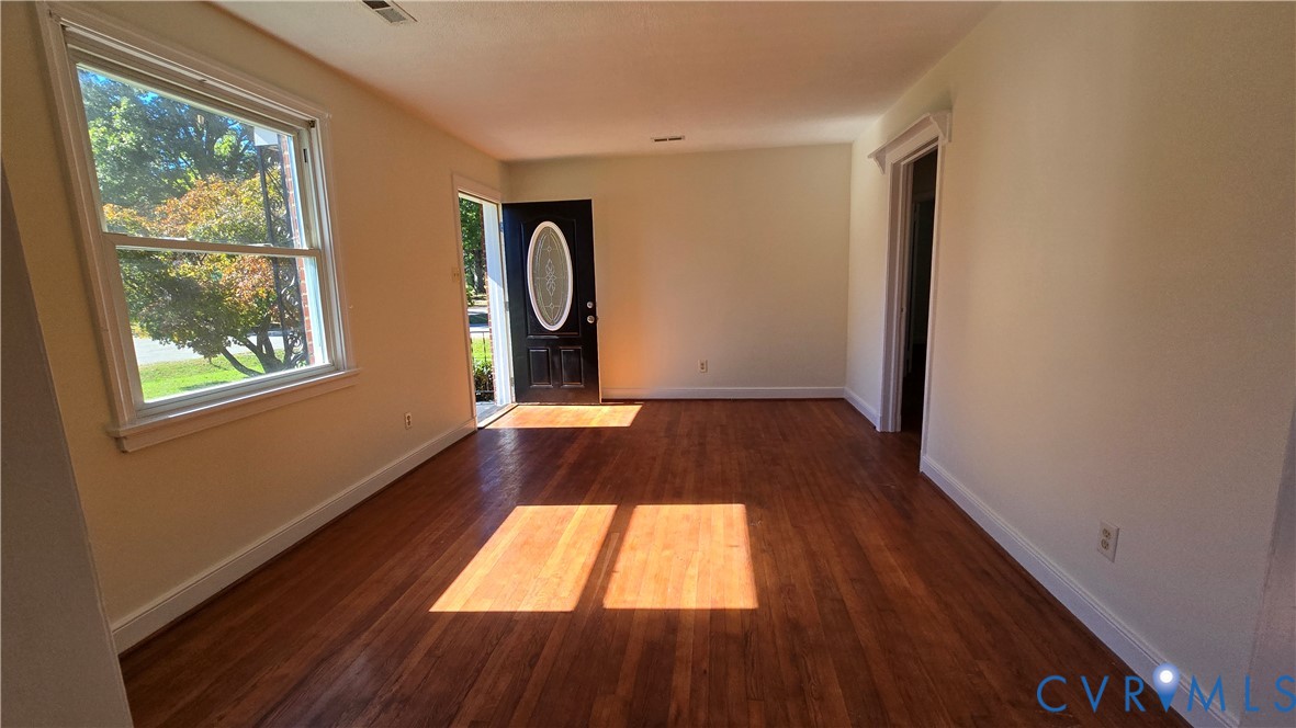 Interior space featuring wood-finish flooring, a large window, and an exterior door with an oval glass insert Interior space featuring wood-finish flooring, a large window, and an exterior door with an oval glass insert