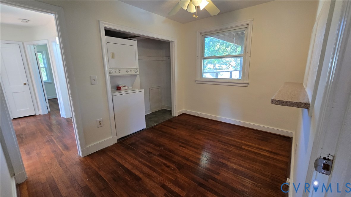 Wood-finish flooring, recessed laundry area with stacked laundry appliances, ceiling fan, and built-in wall ledge Wood-finish flooring, recessed laundry area with stacked laundry appliances, ceiling fan, and built-in wall ledge