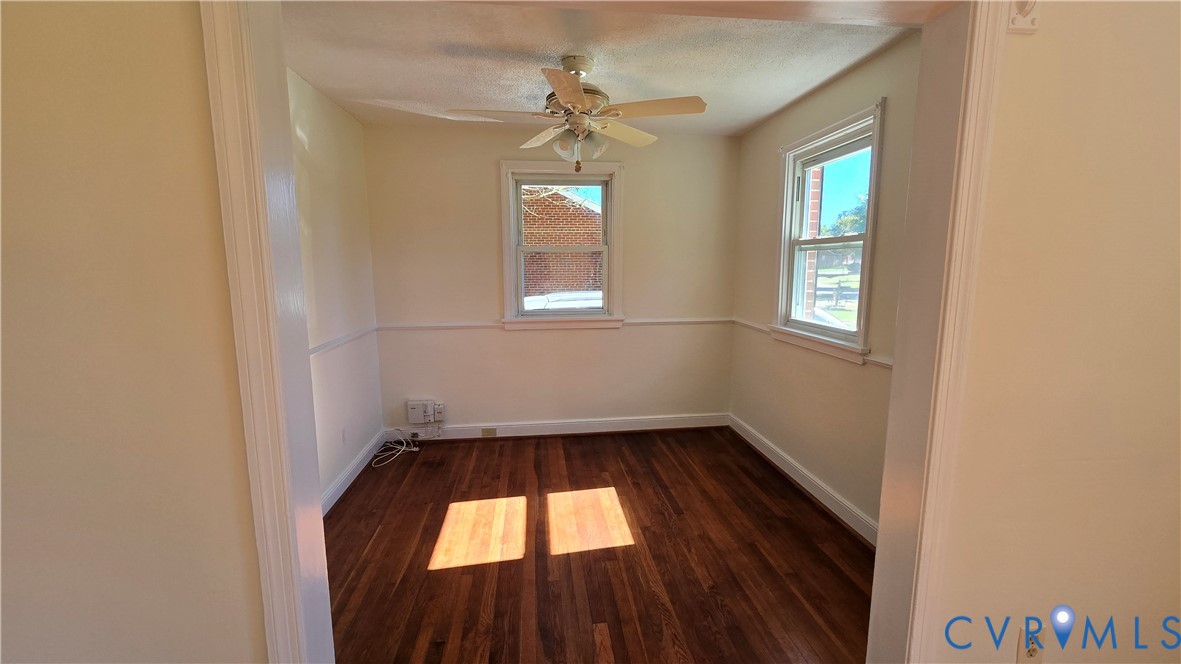 Wood-finish flooring, chair rail molding, dual-pane windows, and a ceiling fan with integrated lighting Wood-finish flooring, chair rail molding, dual-pane windows, and a ceiling fan with integrated lighting