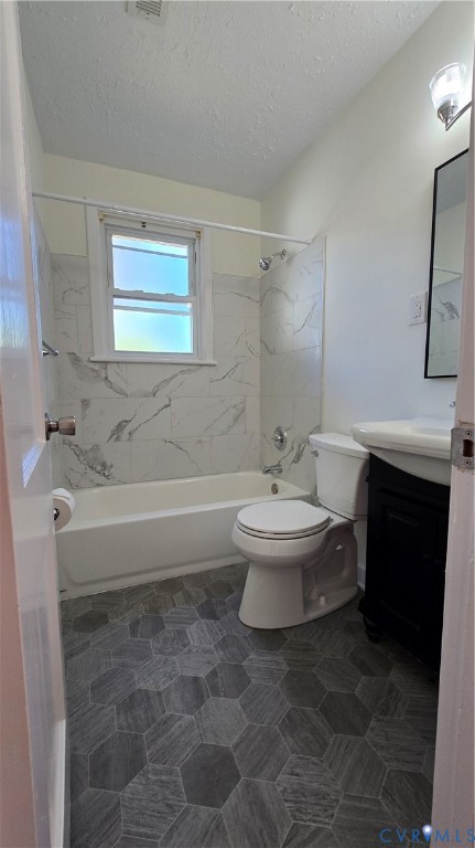 Bathroom featuring gray hexagonal floor tile, white tub surround with stone-patterned tiling, wall-mounted vanity, and a framed mirror