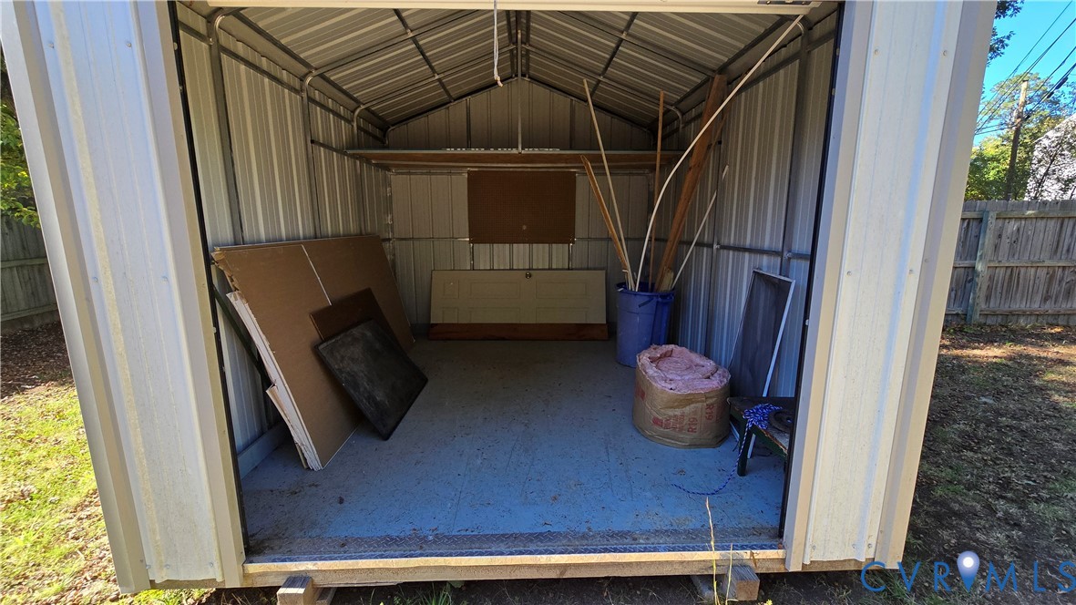 Detached storage structure featuring metal wall panels, a peaked roofline, reinforced metal framing, and a level floor surface