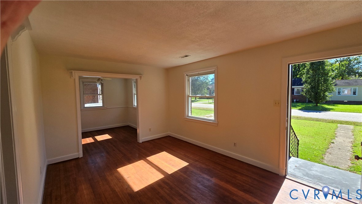 Interior featuring wood-finish flooring, white wall trim, and multiple windows providing natural light Interior featuring wood-finish flooring, white wall trim, and multiple windows providing natural light