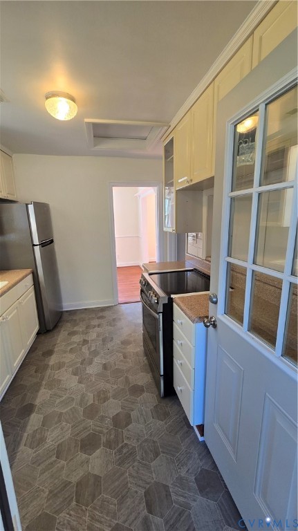 Kitchen featuring hexagon tile flooring, stainless steel range, stainless steel refrigerator, white cabinetry, and a glass-paneled exterior door
