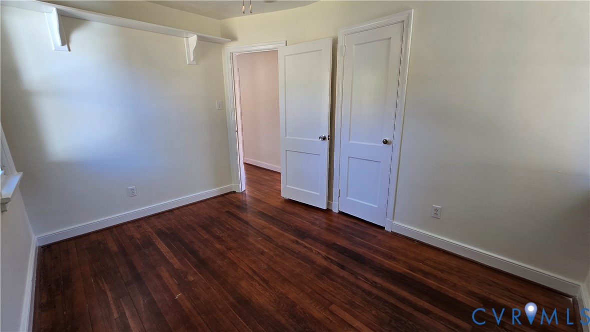 Room featuring wood-finish flooring, two-panel interior doors, and built-in wall shelving