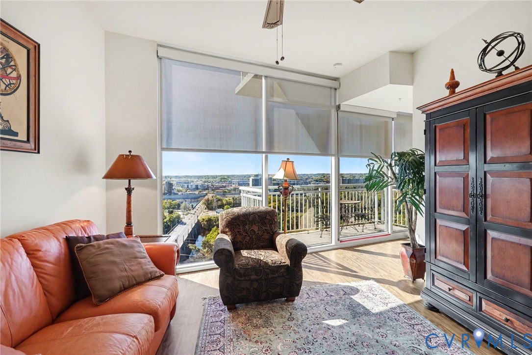 Floor-to-ceiling windows, wood-finish flooring, and access to a railed balcony