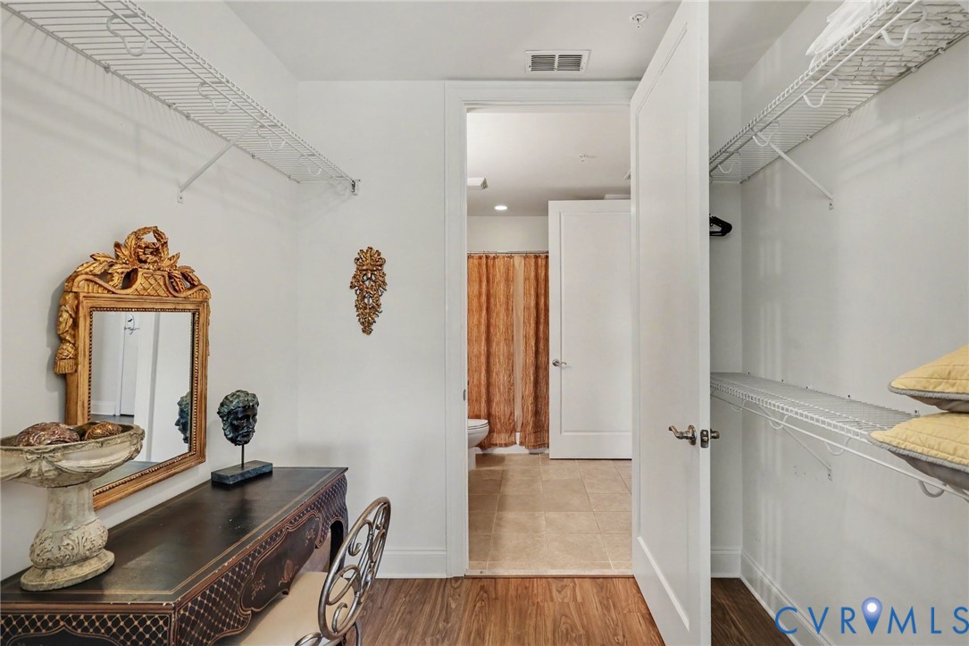 Walk-in closet featuring dual-tier wire shelving, wood-finish flooring, and a solid-core interior door