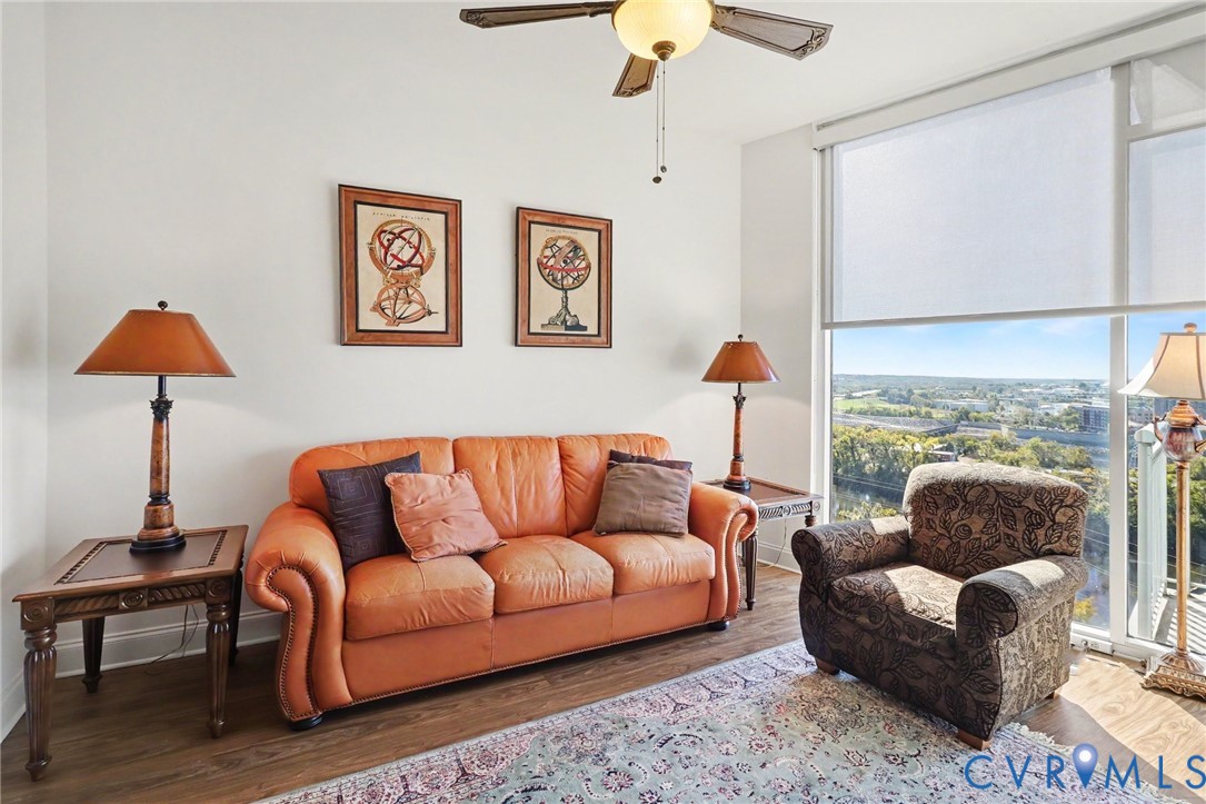 Floor-to-ceiling windows, wood-finish flooring, and ceiling fan with integrated lighting